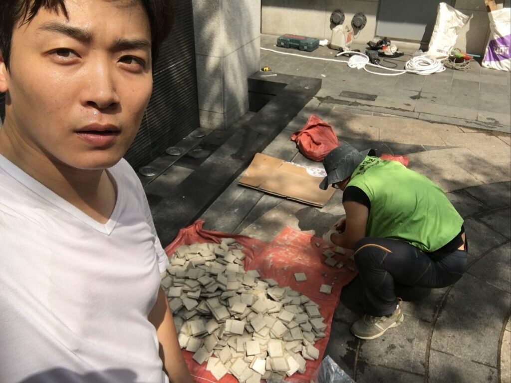 떼어낸 외벽 타일을 천 위에 모아두고 한 장씩 다듬는 작업 현장
