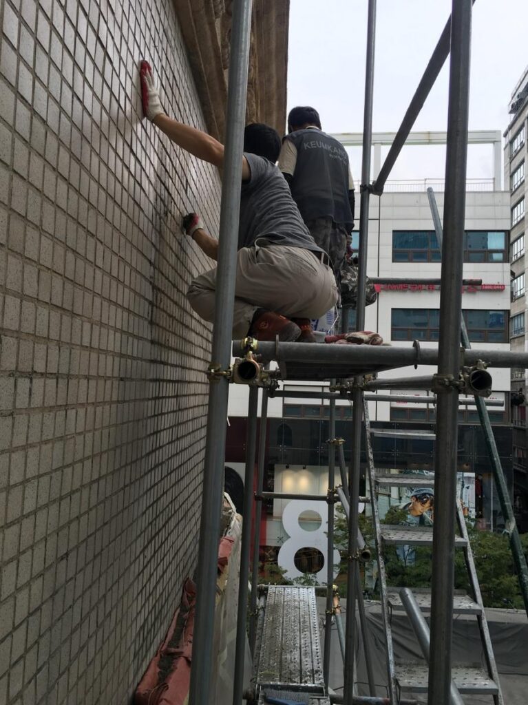 명동예술극장 외벽 비계 위에서 타일면을 작업하는 모습
