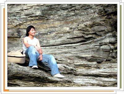 부안 채석강의 층리 진 바위에 기타 케이스를 놓고 앉아 있는 모습